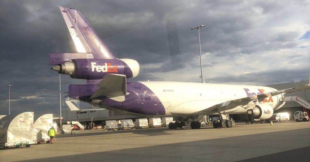 FedEx aircraft cargo freighter parked sydney airport under stormy skies one world courier