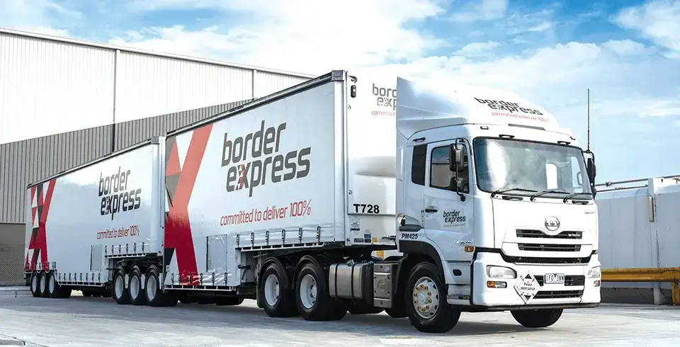 white truck with red and black writing parked at a warehouse