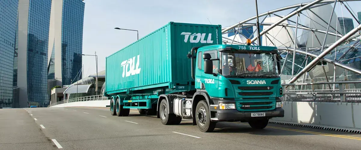 teal truck driving on a road with a city in the background